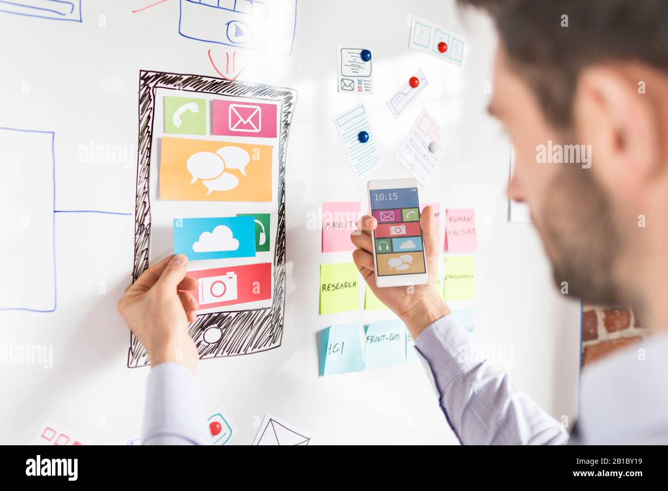 Designer man drawing website ux app development and holding smart phone on hand. User experience concept. Stock Photo