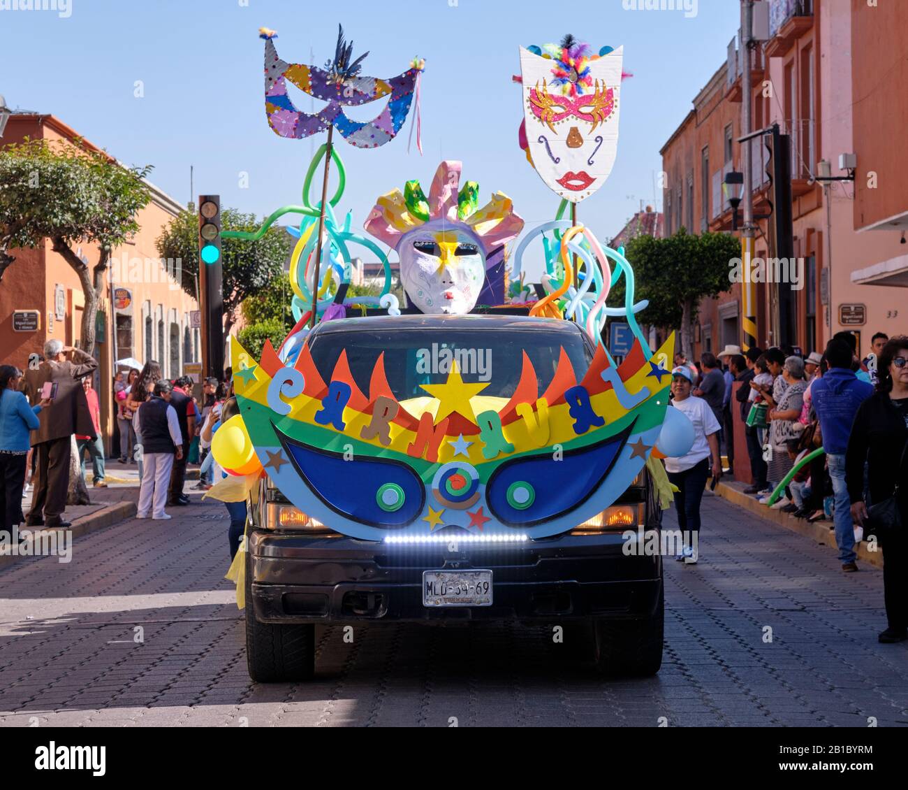 Decorated Float with word Carnaval in the kids parade of the Tlaxcala Carnival featuring Litters of Huehues in traditional Mexican costumes. Stock Photo