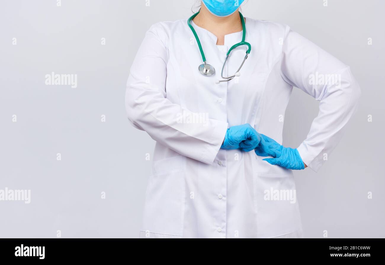 medic woman in white coat and mask, wearing blue medical latex gloves ...