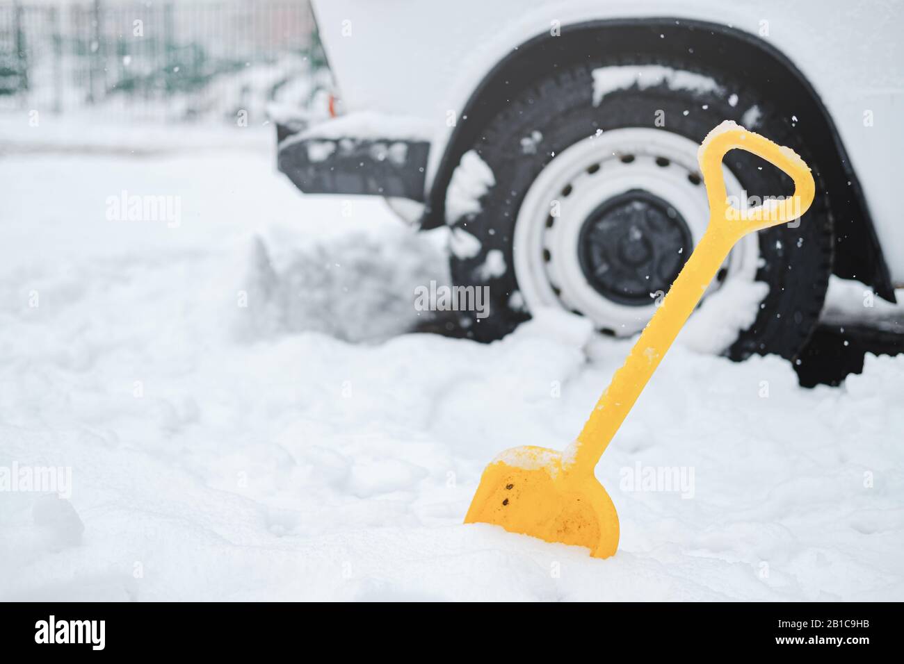 Car wheel in snow and a shovel. Concept of winter traffic problems, digging the vehicle out of the snow Stock Photo