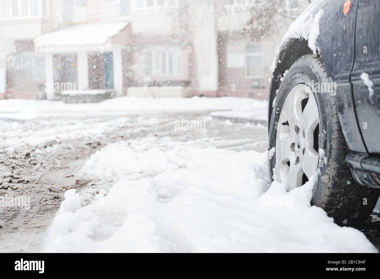 The wheel of a car among wet snow. Traffic, commuting problems caused by the storm in winter Stock Photo
