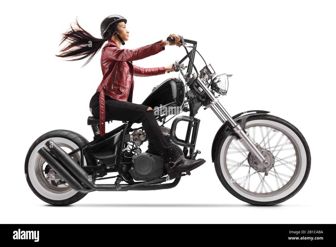 Full length profile shot of a young woman riding a custom black motorcycle isolated on white background Stock Photo