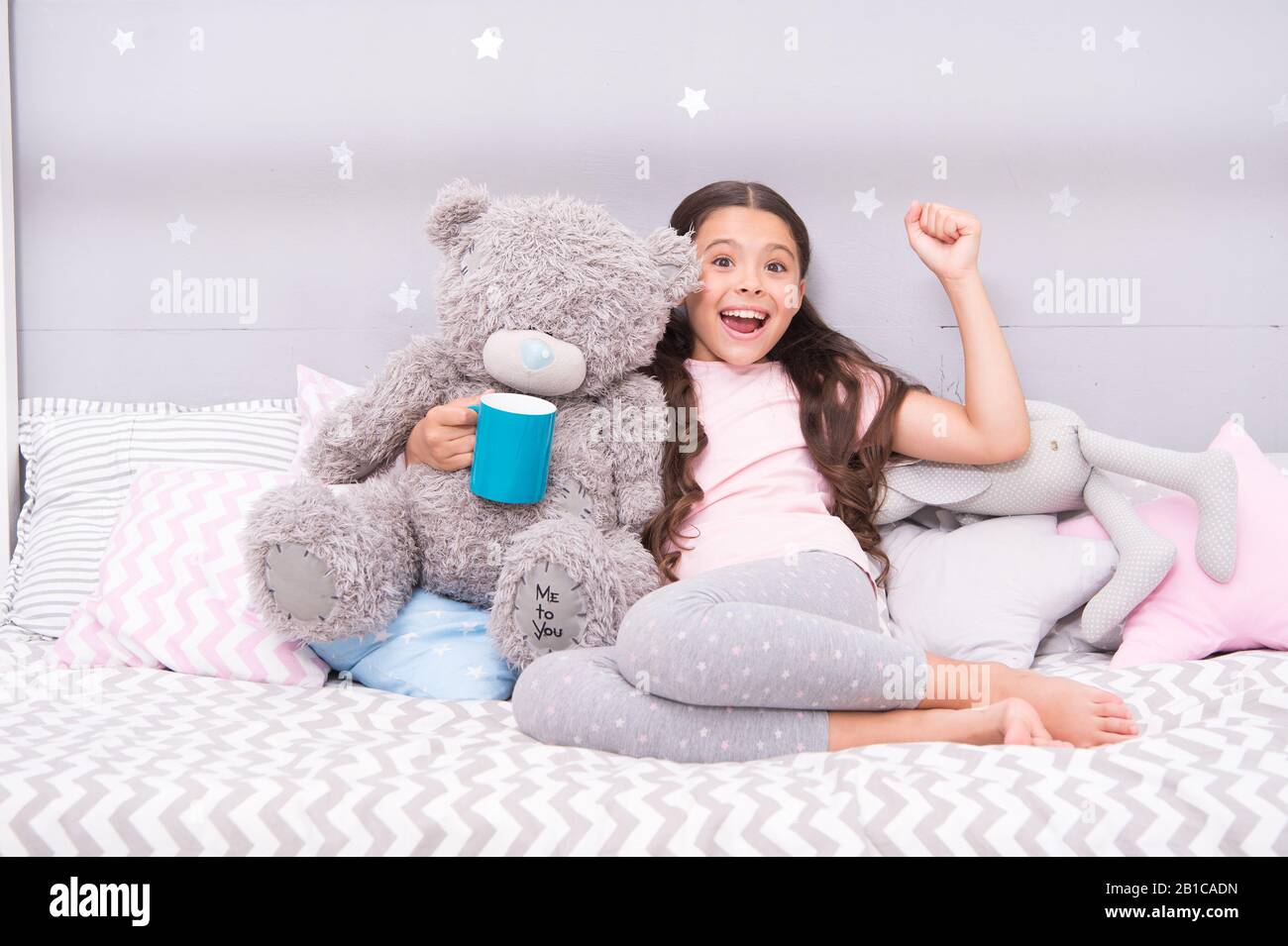 Little child hold mug. Girl in pajamas drinking tea. Relaxation before sleep. Drinking milk just before bed. Bedtime beverage. Hot milk before sleep. Health Benefits Drinking water before bed. Stock Photo
