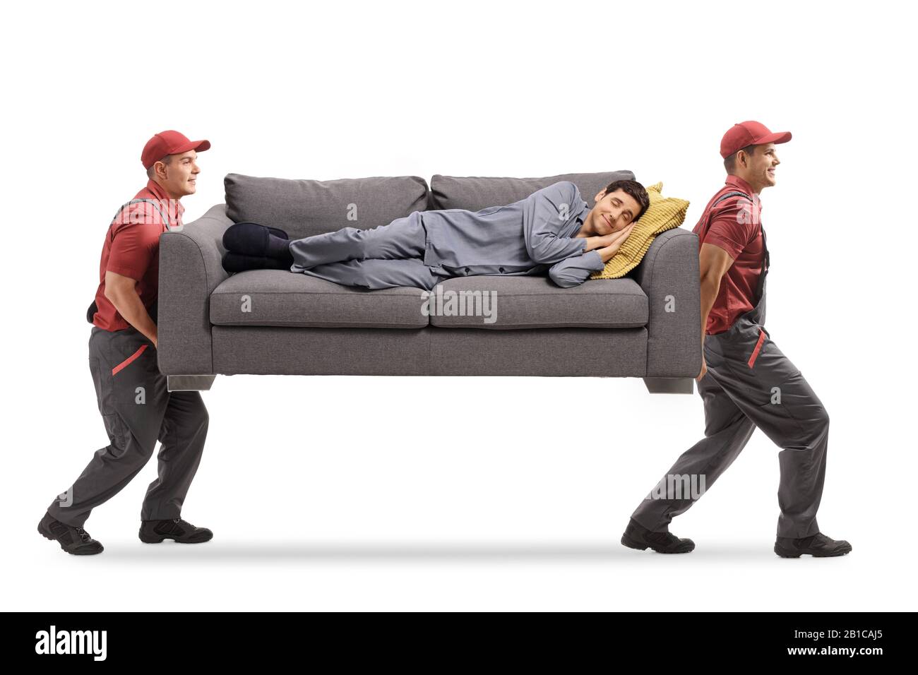 Full length shot of two movers carrying a couch and a man in pajamas sleeping on it isolated on white background Stock Photo