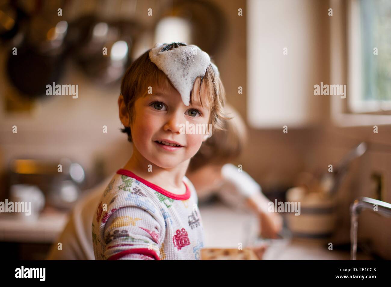 Playful young boys washing dishes after breakfast. Stock Photo