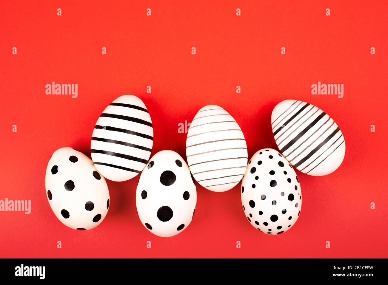 Different graphic hand-painted eggs on bright red background. Easter concept. Flat lay style. Stock Photo