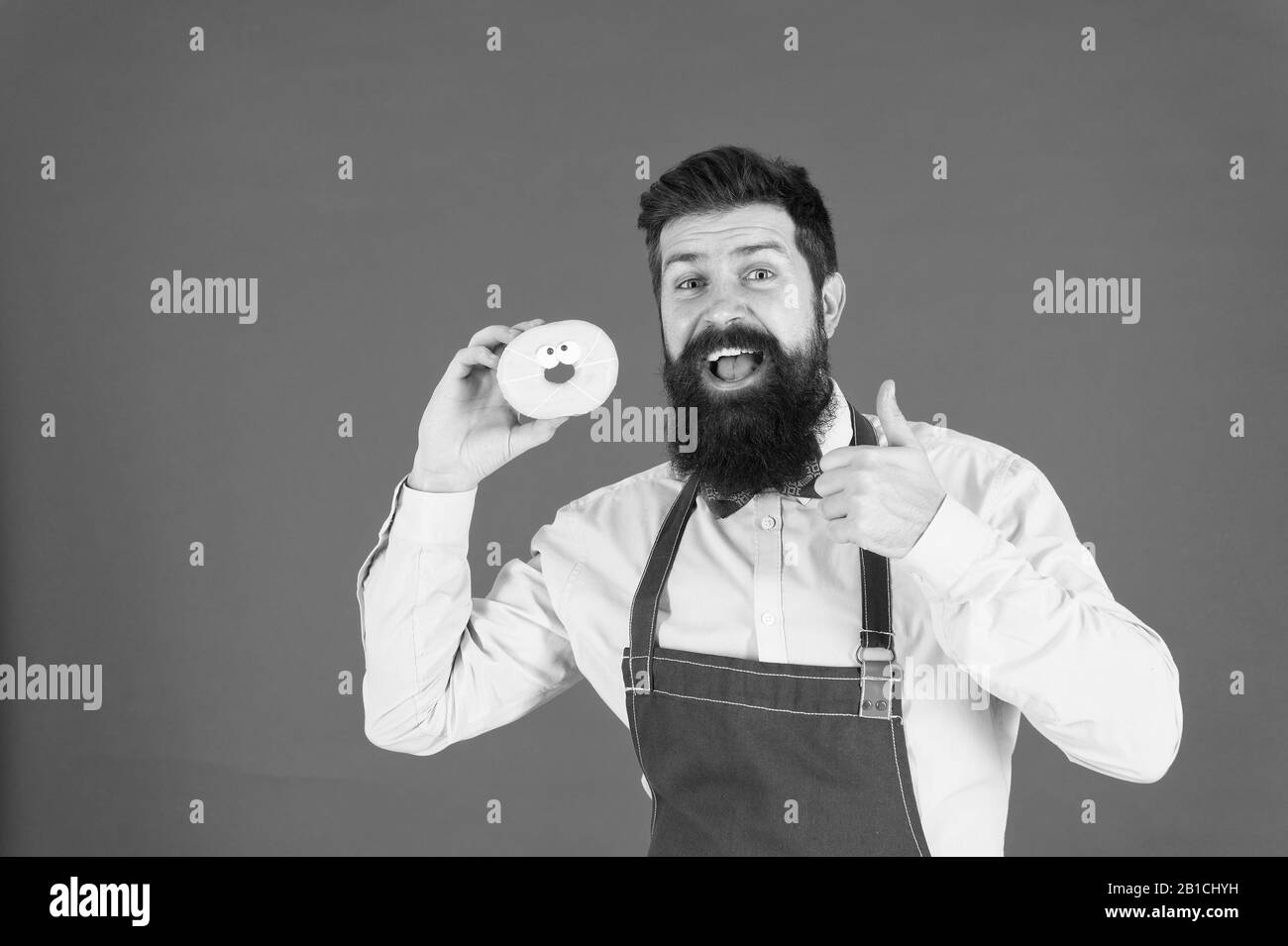 Bearded well groomed man in apron selling donuts. Donut food. Hipster