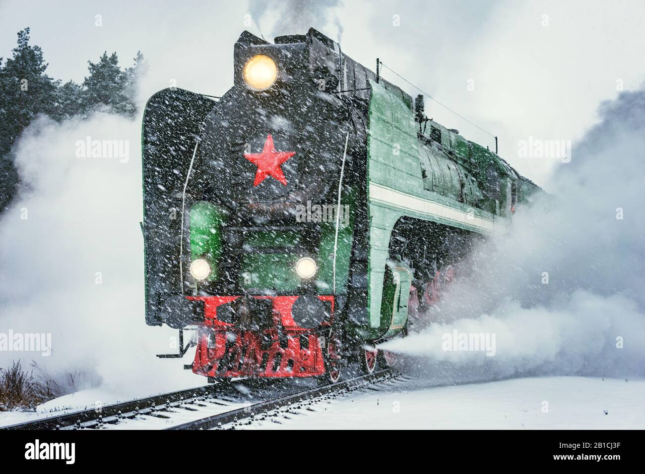 Retro steam train departs from the railway station at winter snowy time ...