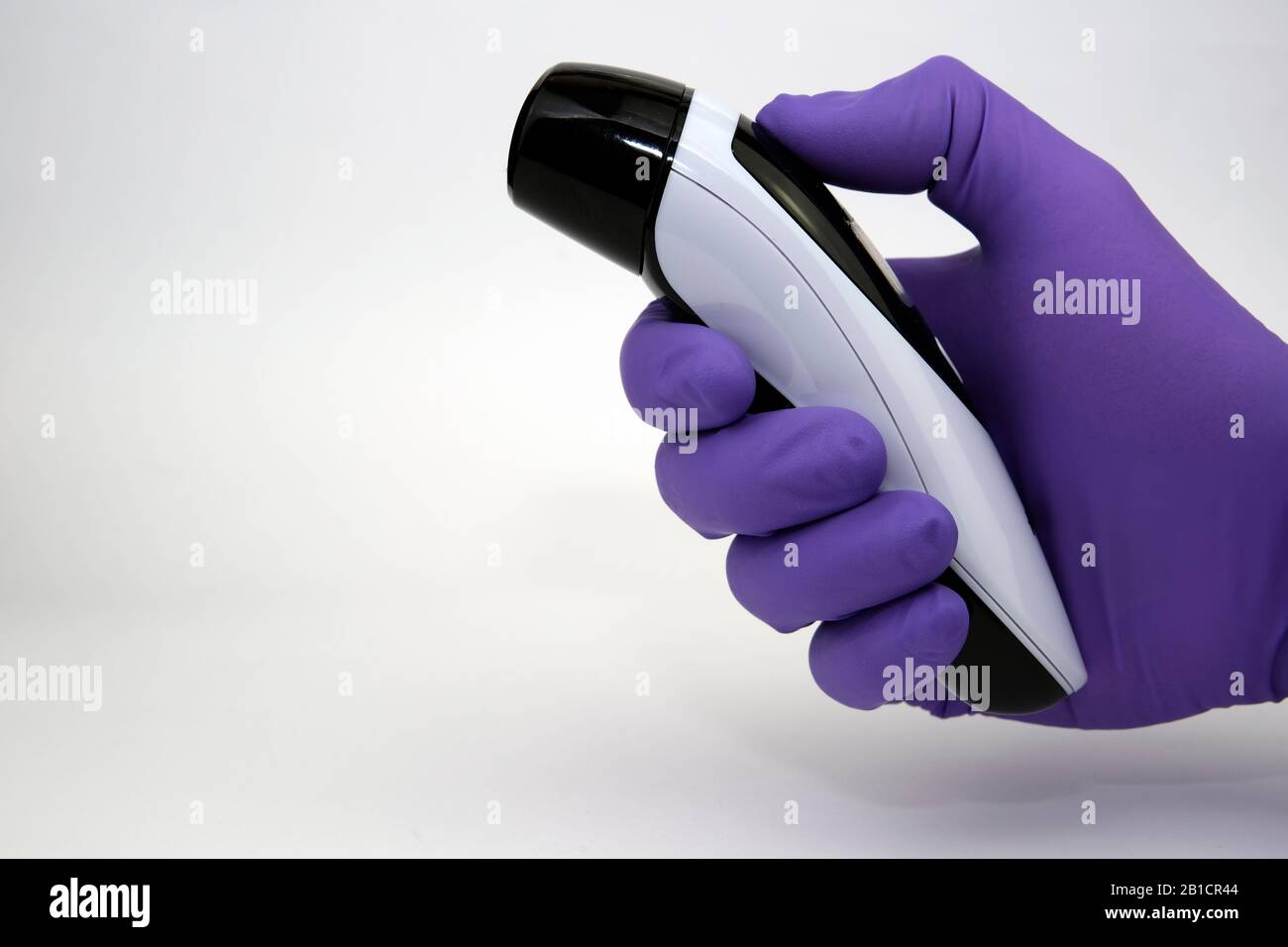 Hand in a glow holding the thermometer for measuring the temperature of the body. Check for coronavirus. Stock Photo