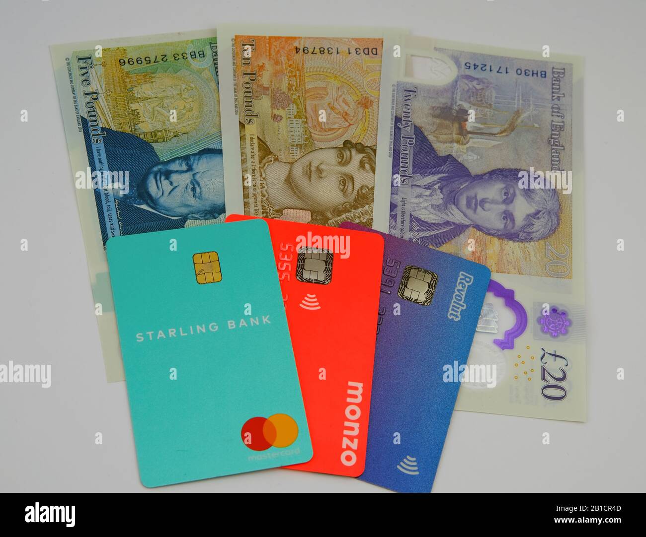 Starling, Monzo, Revolut bank cards on the new polymer pound sterling notes. Concept to highlight similar colour gamma of the British bills and bank. Stock Photo