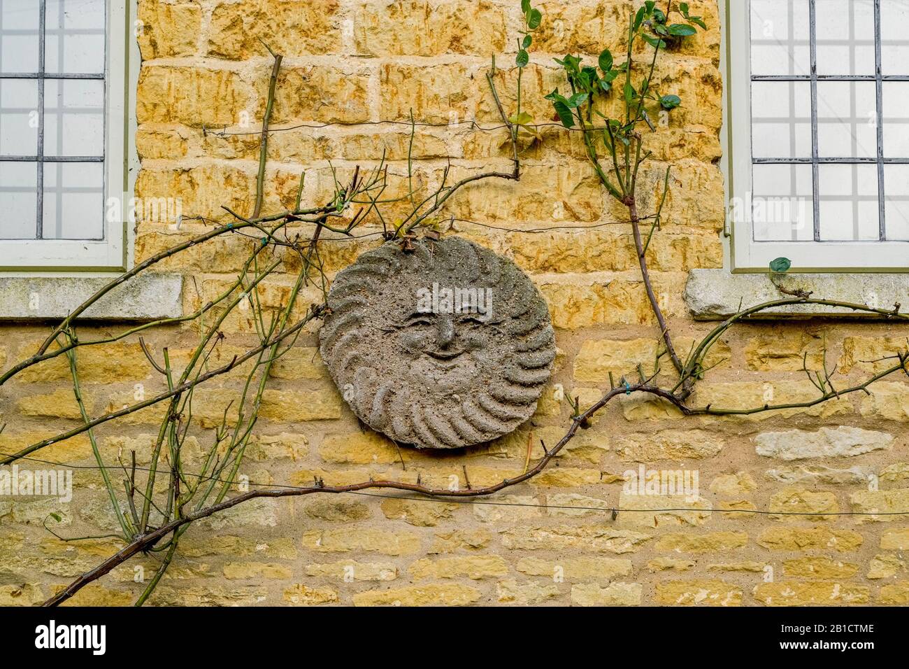 Happy face, clay sun on building, Village of Bourton-on-the-Water, Gloucestershire, England, UK Stock Photo