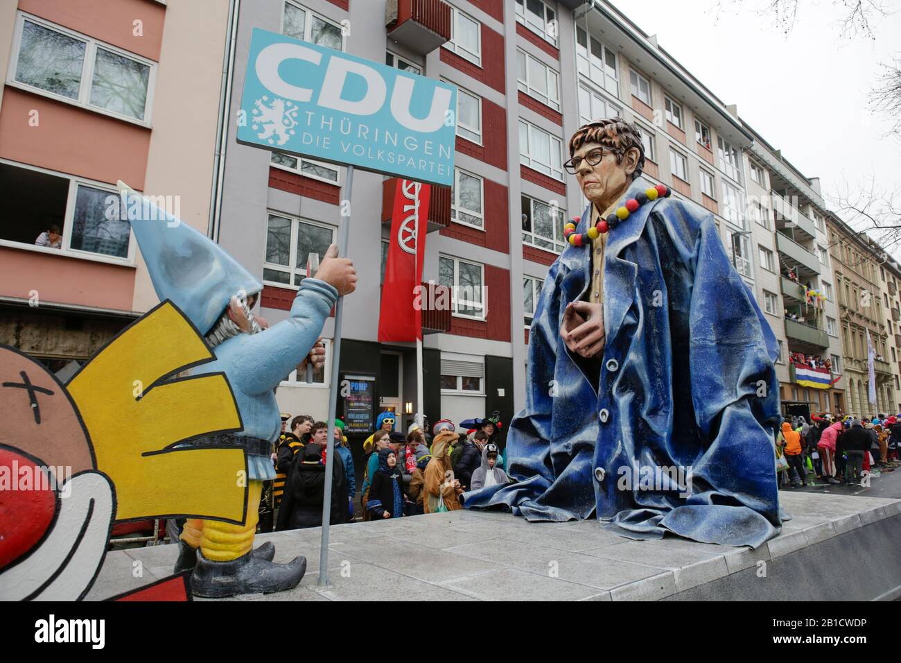 Mainz, Germany. 24th February 2020. The chairwoman of the Christian Democratic Union (CDU) and German Minister of Defence Annegret Kramp-Karrenbauer is depicted on a float in the Mainz Rose Monday parade. She wears an oversized dress of German Chancellor Angela Merkel and dwarf with a STOP sign and a sign reading ‘CDU Thuringia' in front of her, lauding to her not being able to fill Angela Merkel's shoes, especially after the recent scandal after the Thuringia election. Around half a million people lined the streets of Mainz for the traditional Rose Monday Carnival Parade. The 9 km long parade Stock Photo