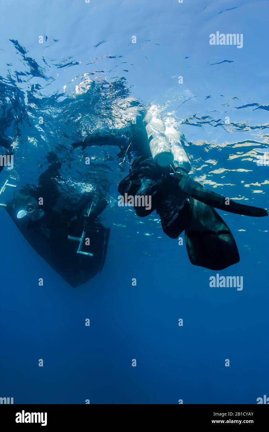 Technical diver reaching boat after deep dive. Stock Photo