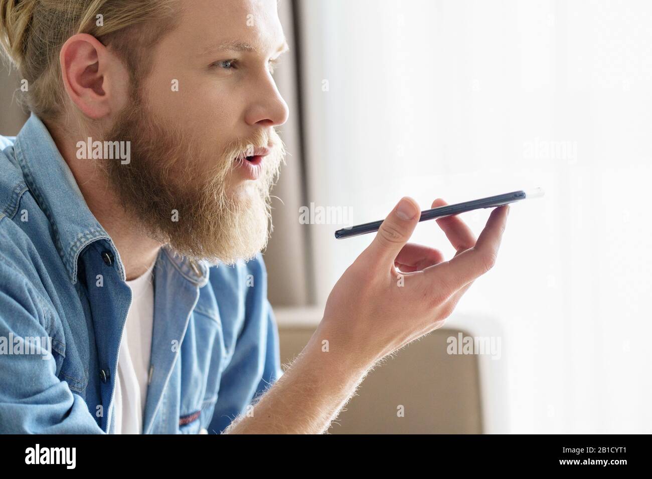 Young man activate virtual digital voice assistant on mobile phone Stock Photo