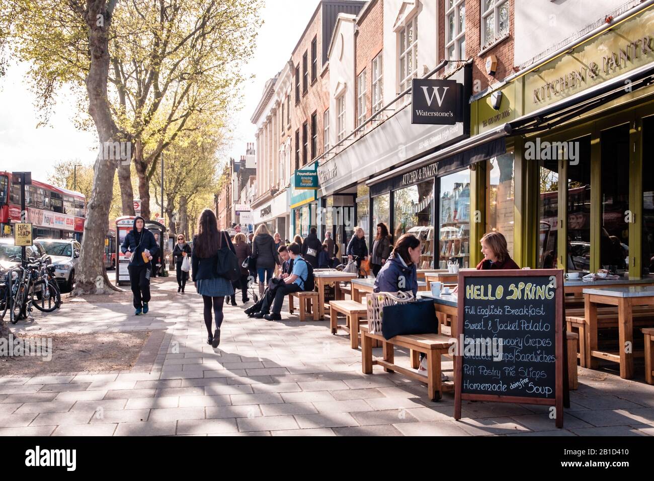 Pedestrians and restaurant patrons on Chiswick High Street on a sunny spring day, London, England Stock Photo