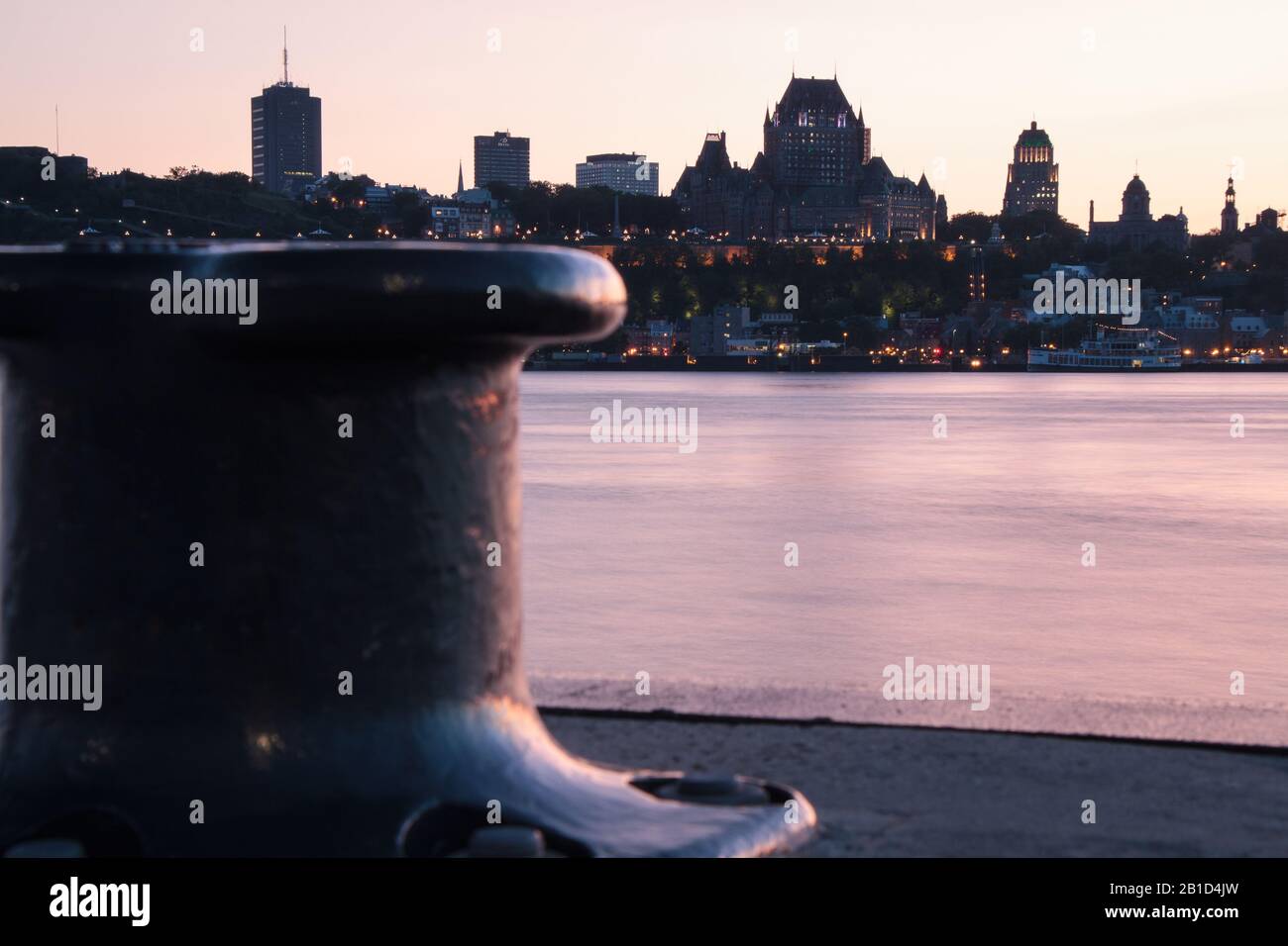 Famous Hotel Chateau Frontenac Castle of Quebec city seen from the other side of the saint lawrence river after sunset at blue hour with bitt (dock) Stock Photo