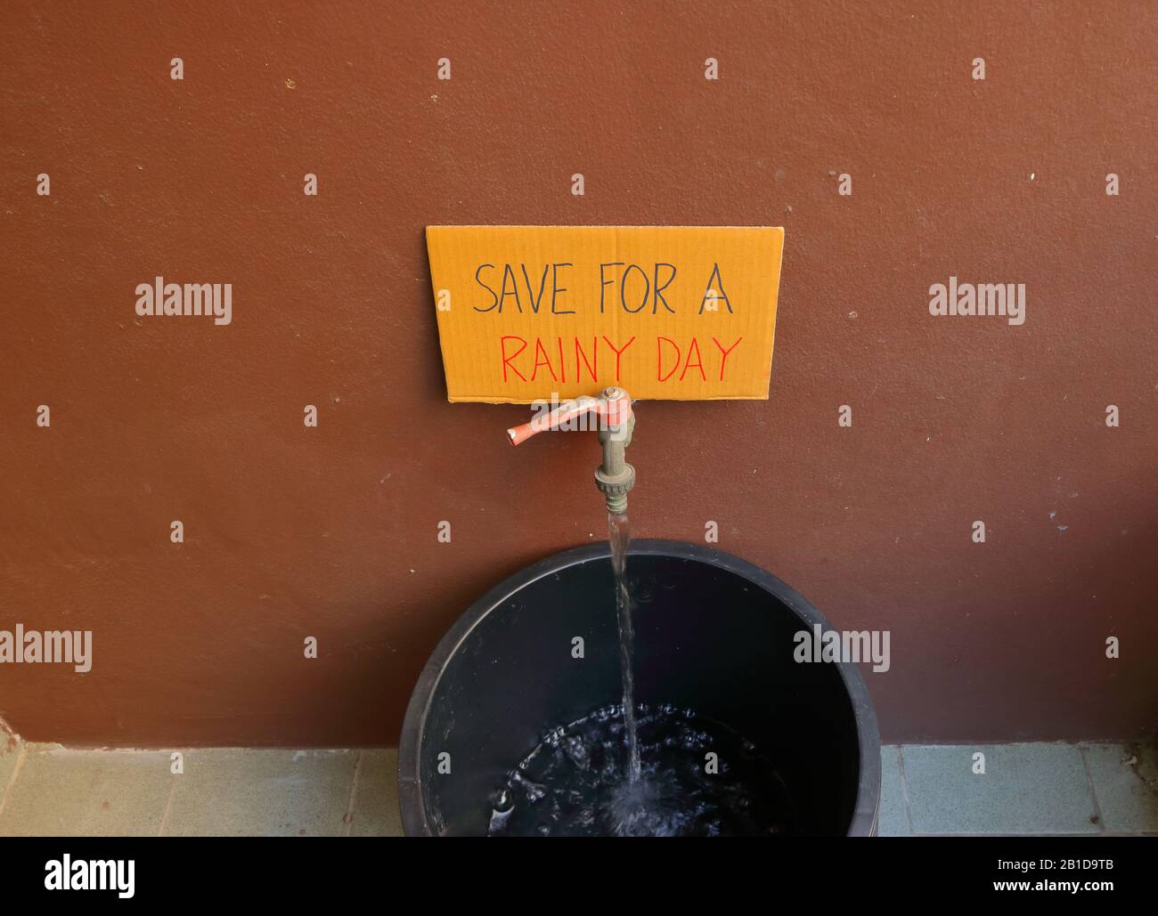 Cardboard Sign Contains Handwriting SAVE FOR A RAINY DAY Placed On 