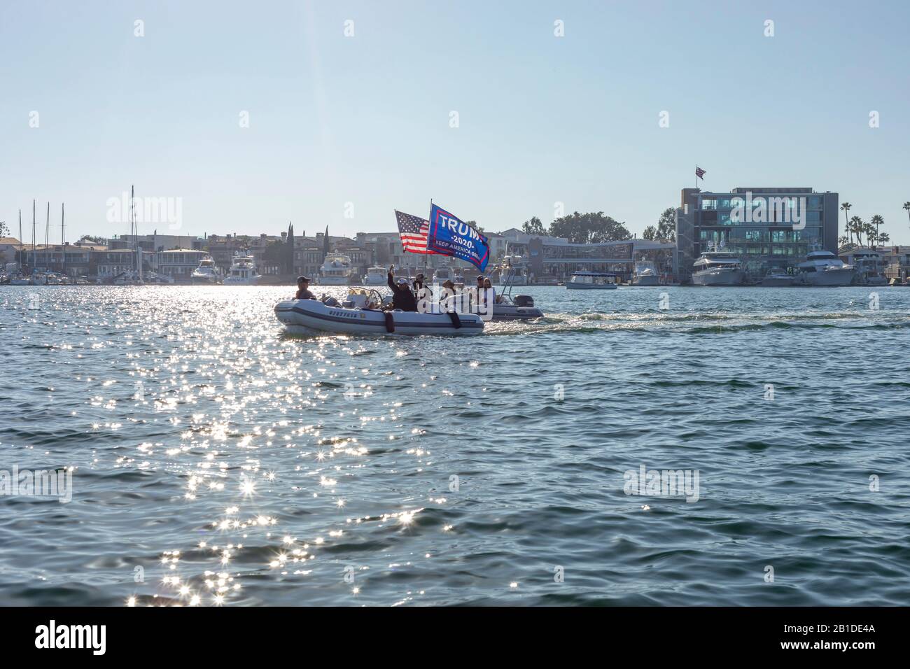 Boaters cruise Newport Bay with and American Flag and a Trump flag flying from their boats. Newport Bay, California, USA. Stock Photo