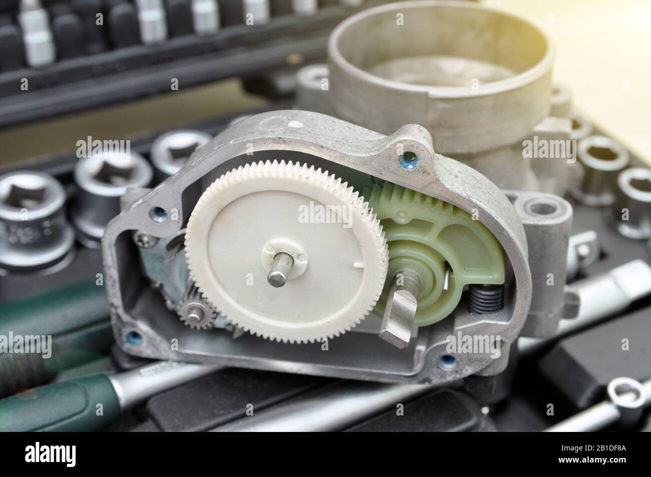 Repair and cleaning the car throttle. Analysis of the throttle on the background of a set of tools for car repair. Gears, mechanism. Stock Photo