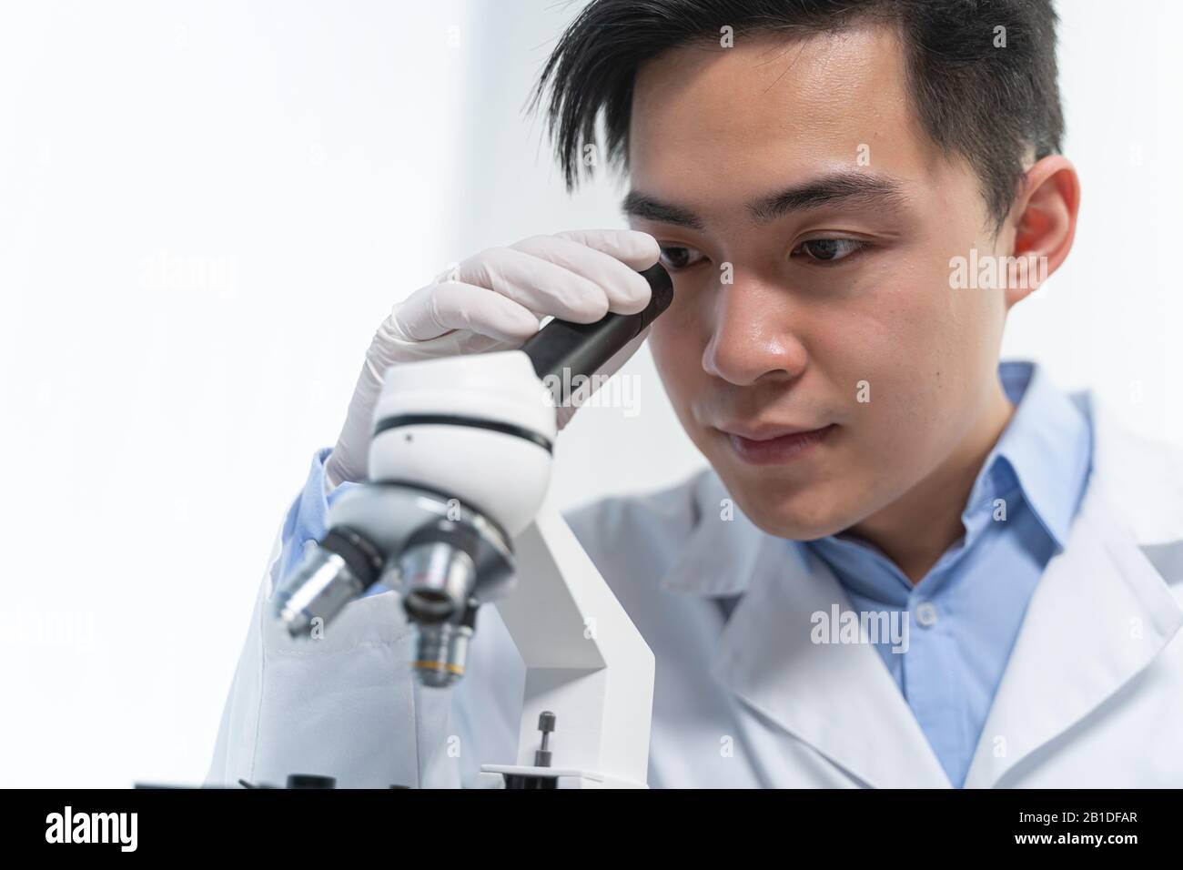 Kind young researcher looking through a microscope Stock Photo