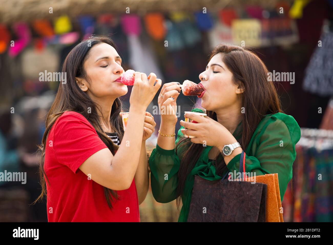 Two women eating flavored ice gola dipped in syrup Stock Photo