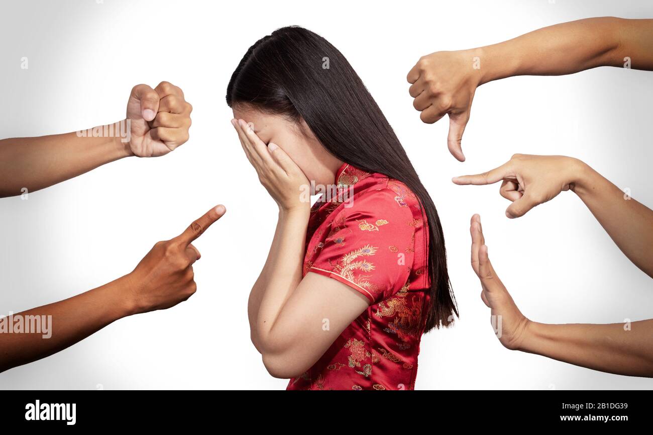 Asian woman in Chinese costume covered her face with regret for being racism and hate surrounded by hands mocking her, scoffing in the outbreak situat Stock Photo