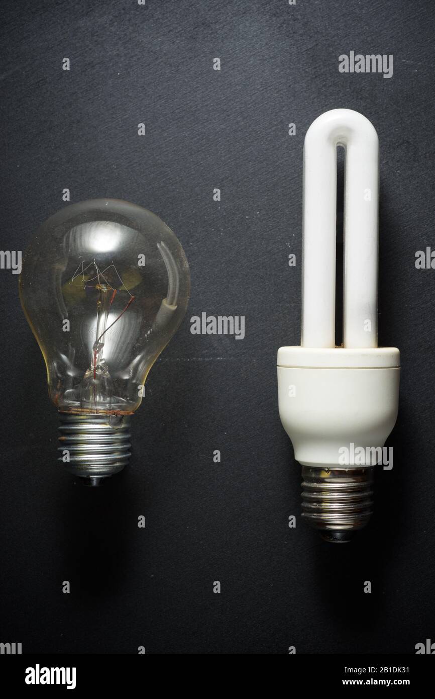 An old incandescent bulb and a modern bulb on a black table Stock Photo