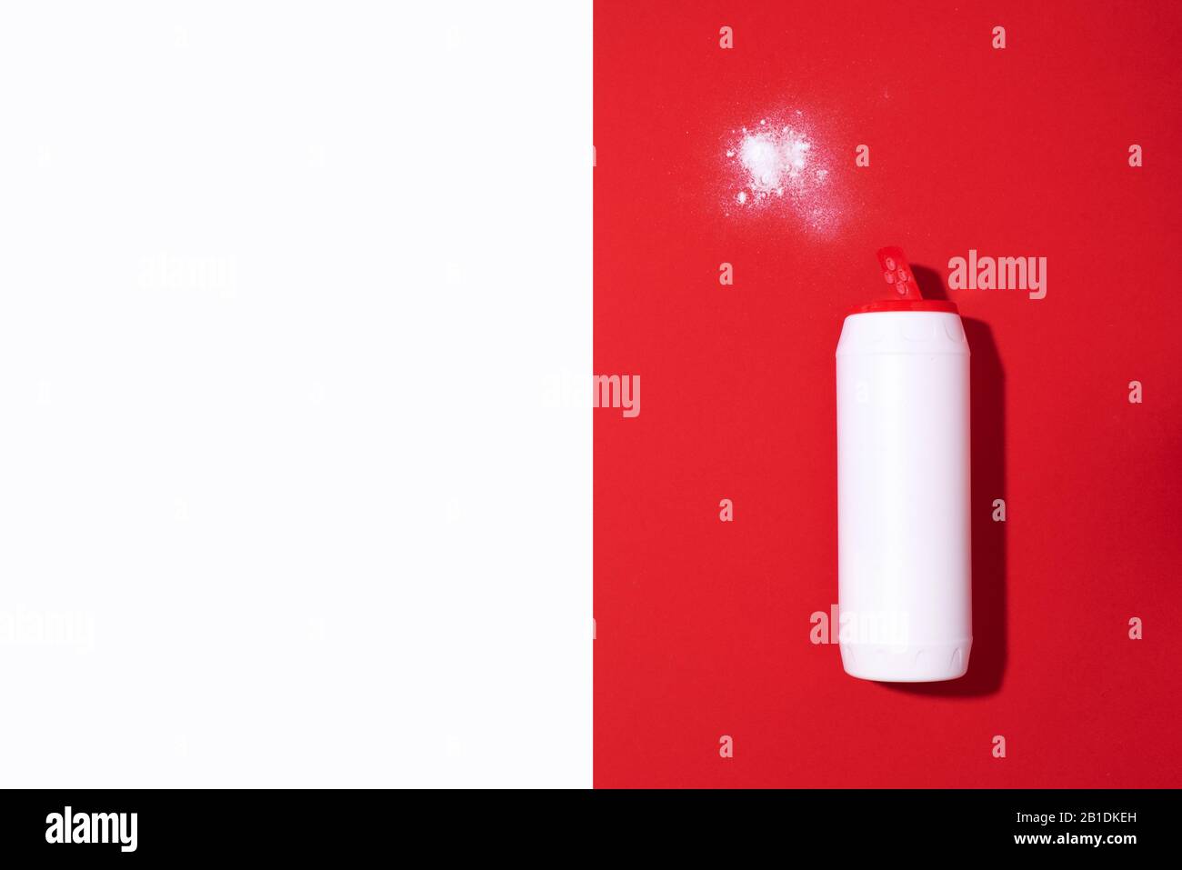 White plastic bottle of detergent powder or cleaning agent on red background. Copy space. Top view. Flat lay. Household chemicals concept. Stock Photo