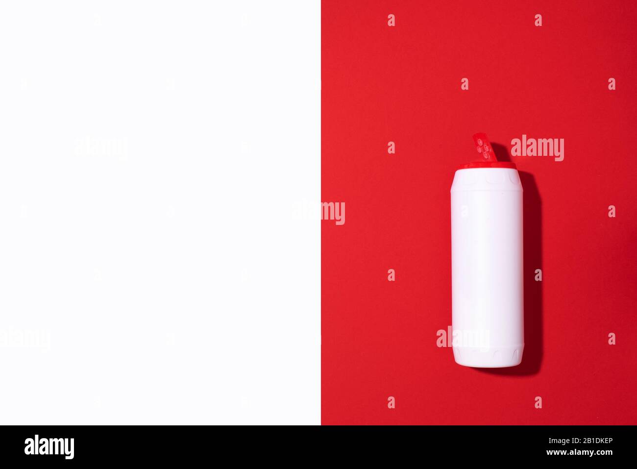 White plastic bottle of detergent powder or cleaning agent on red background. Copy space. Top view. Flat lay. Household chemicals concept. Stock Photo