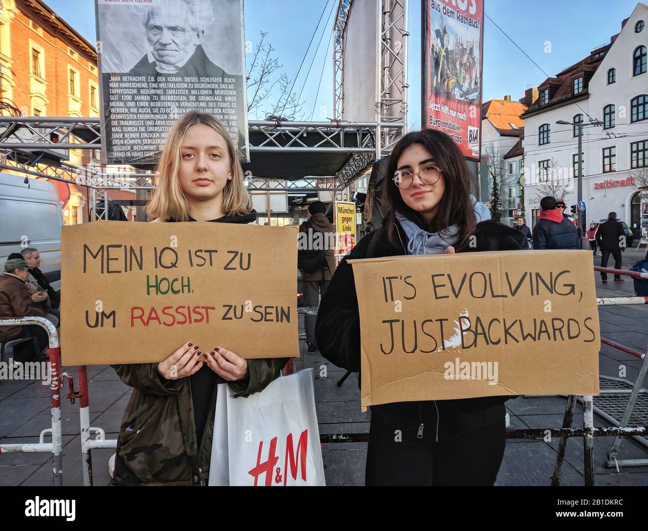Munich, Germany. 25th Feb, 2020. ''My IQ is too high to be a racist''. Two protesters against hate and neonazis demonstrate against the right extremist Pegida Munich and neonazi BIA groups innthe Pasing district. As the group hides their extremist backgrounds, protestors inform passersby of the reality. As hate and racism escalate in Germany people are demanding an end to the permissiveness and passiveness they believe is leading to radicalization and murders. Credit: ZUMA Press, Inc./Alamy Live News Stock Photo
