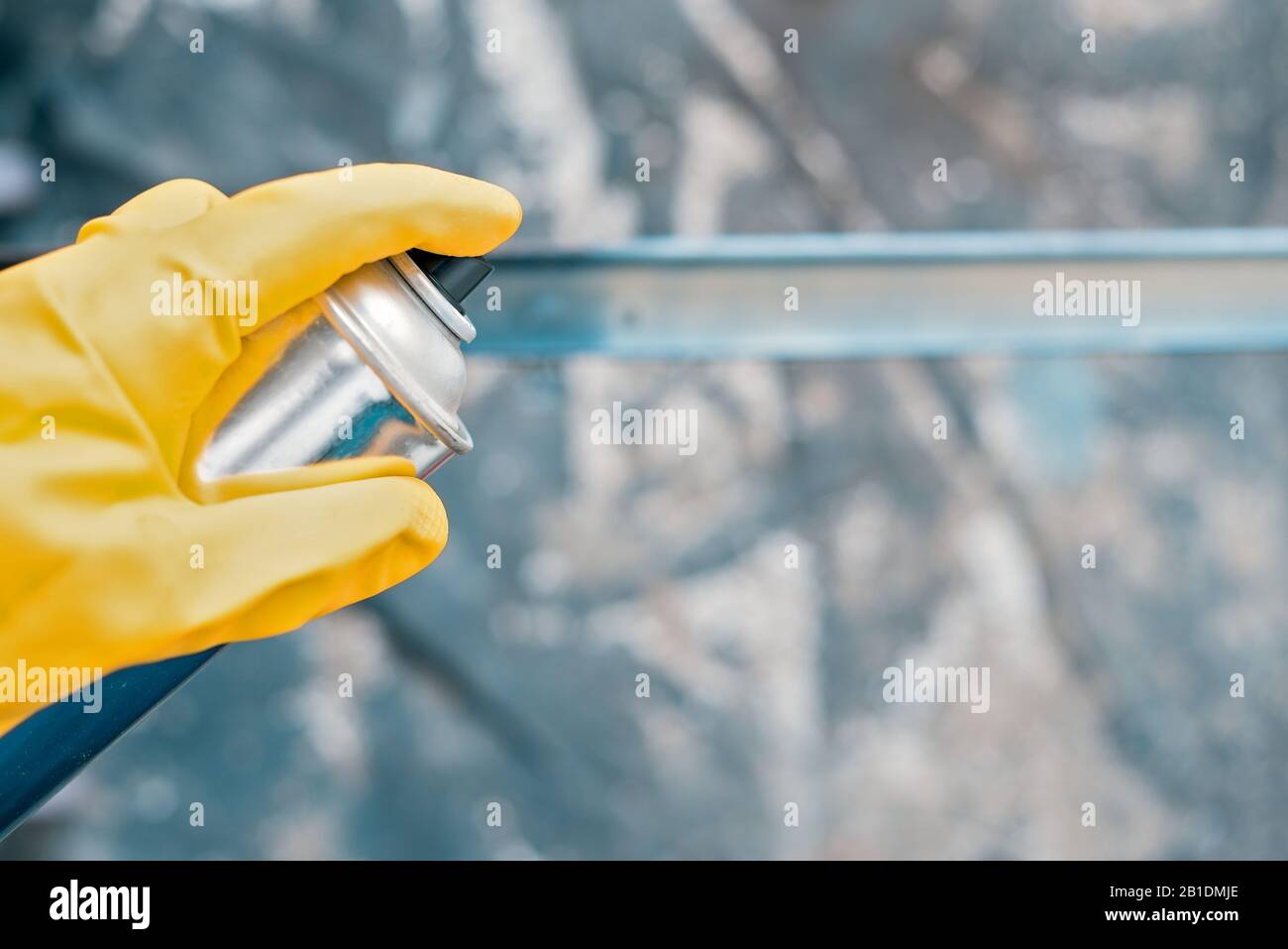 spray paint. hand in yellow rubber glove holding a spray bottle ...