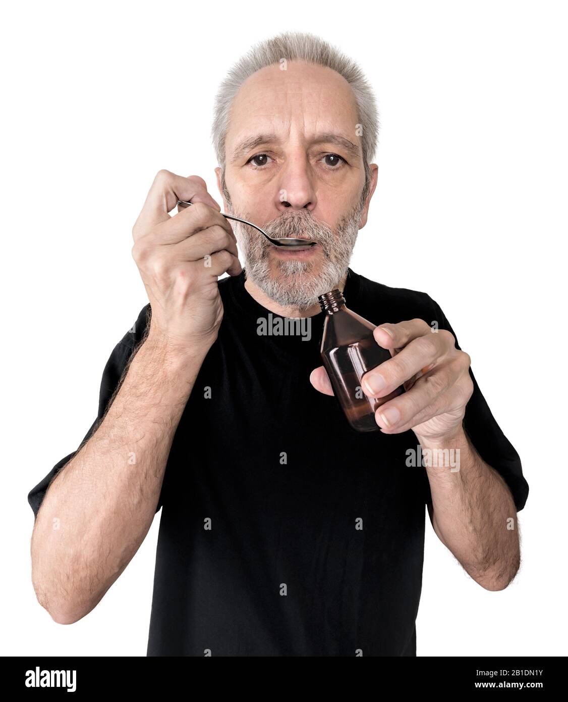 A mature man is drinking a spoon of  cough syrup to cure his sore throat and bronchitis. Isolated on white background Stock Photo