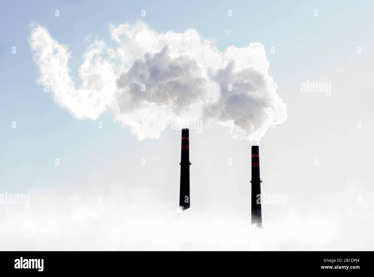Plumes of white smoke coming out of smokestacks against sunny skies Stock Photo