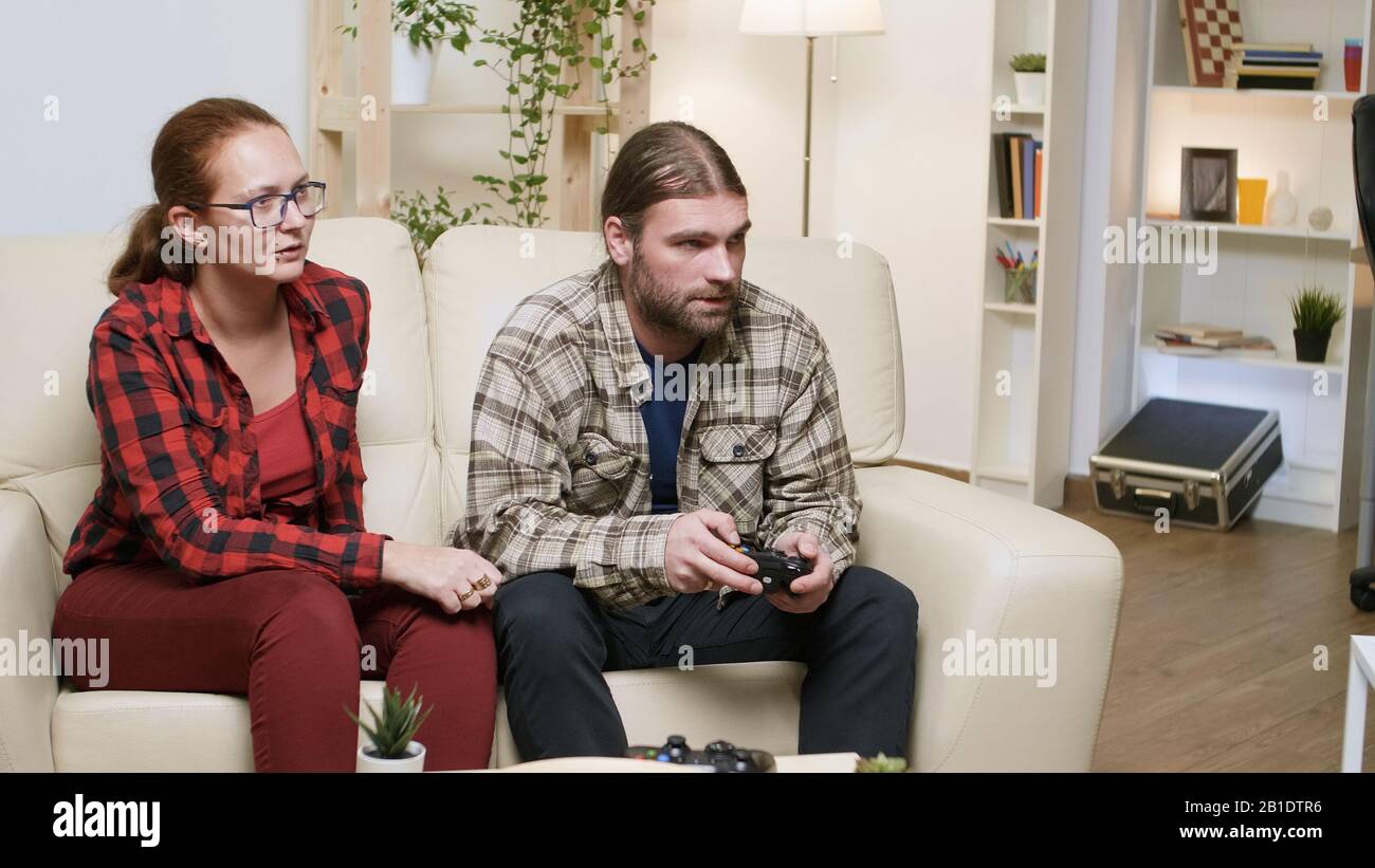 Man yelling at his girlfriend after losing while playing video games. Man using wireless controller. Stock Photo