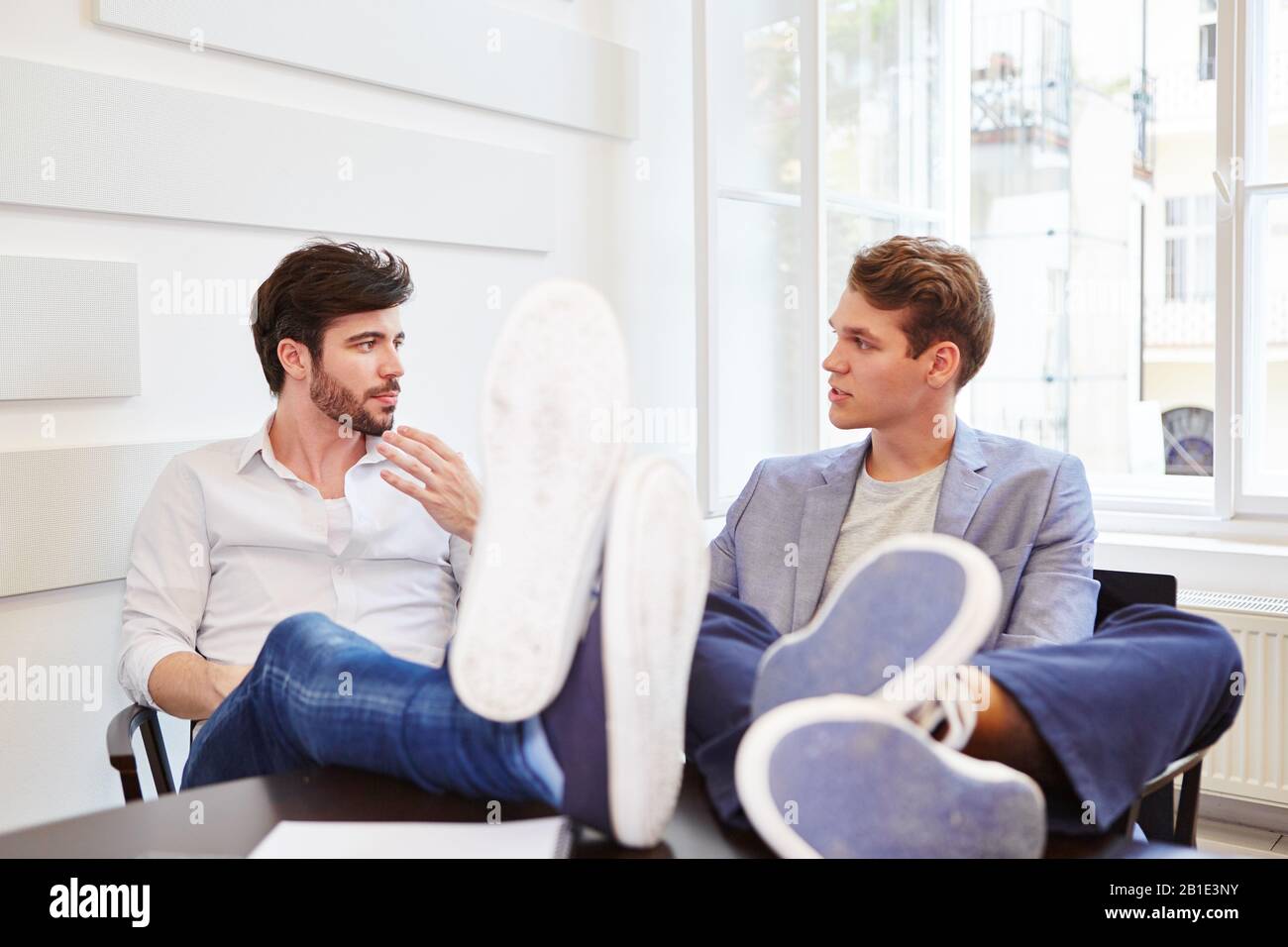 Two young business people talk to each other in the office Stock Photo