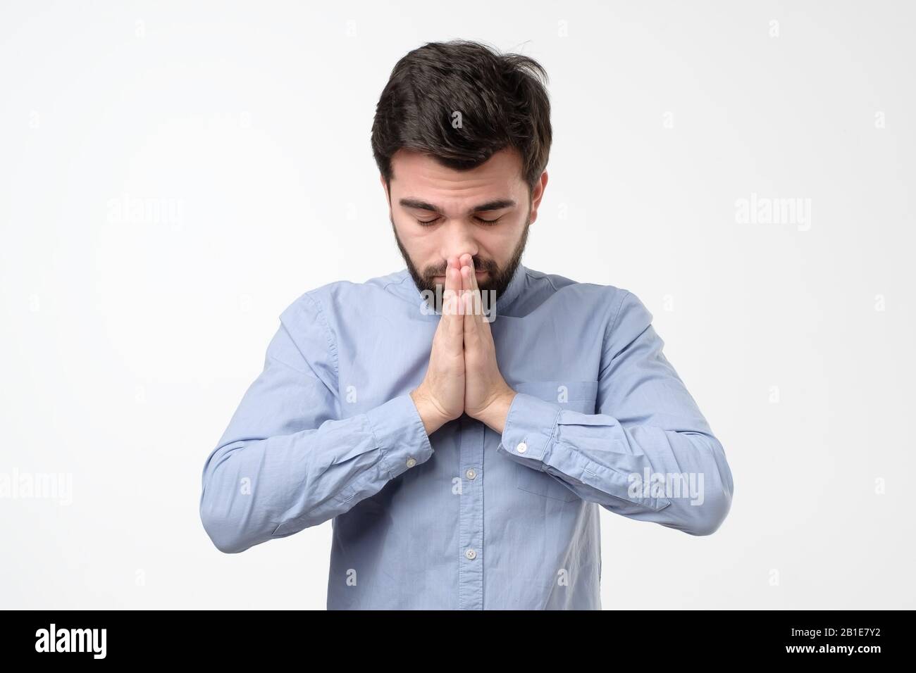 Religious expressive hispanic man praying in studio on white isolated background Stock Photo