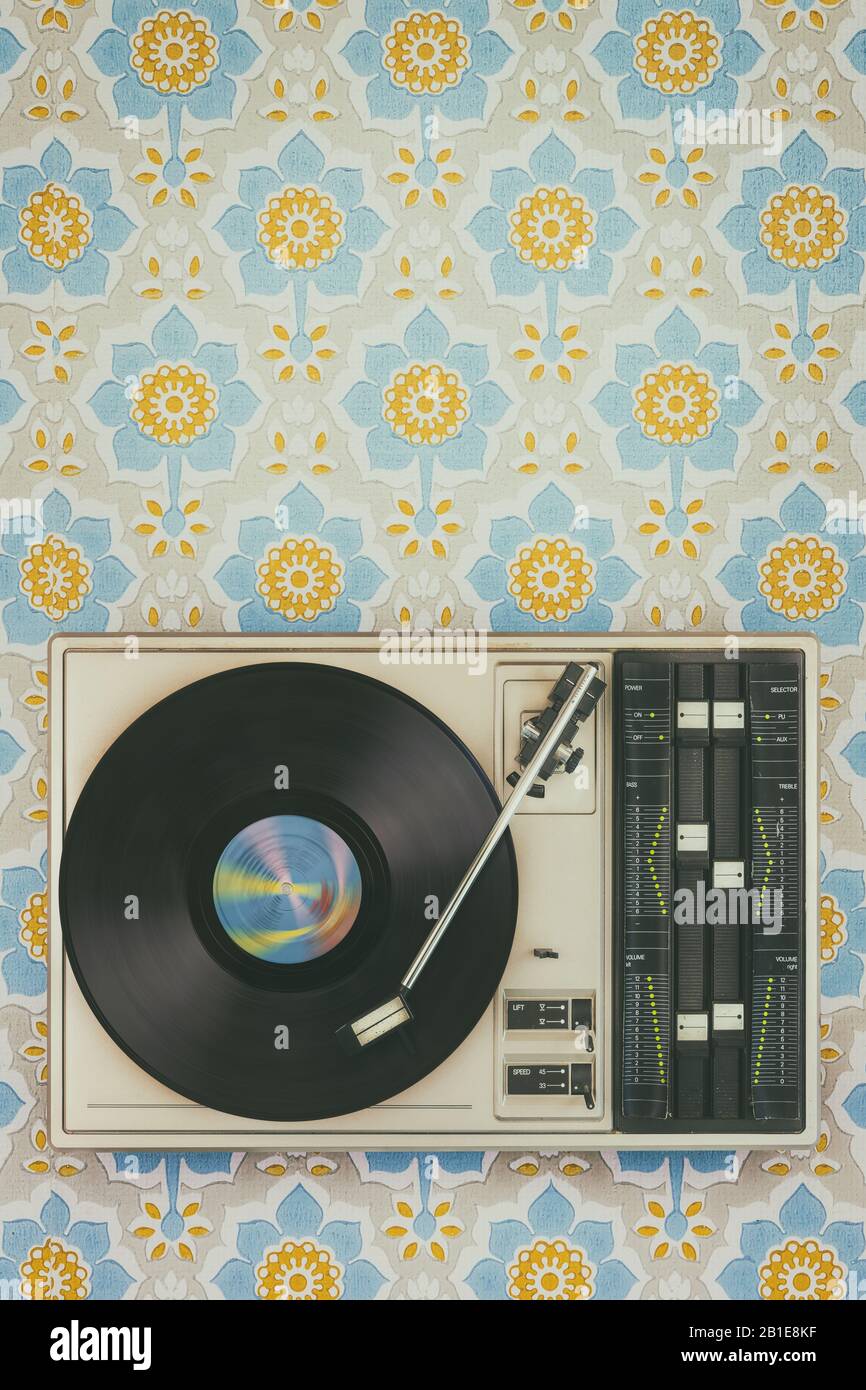 Retro styled image of an old record player on top of flower wallpaper Stock Photo