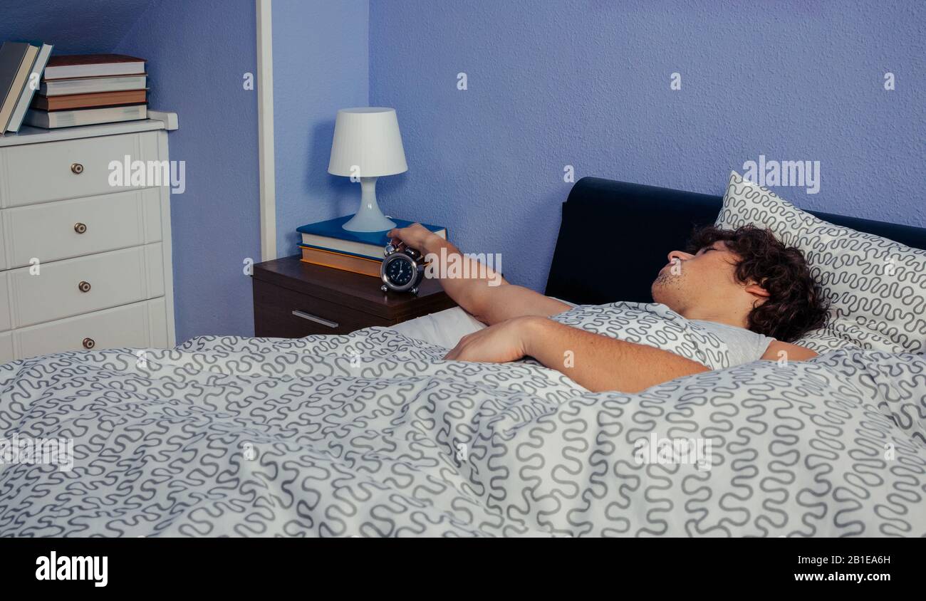 Young man stopping the alarm clock Stock Photo