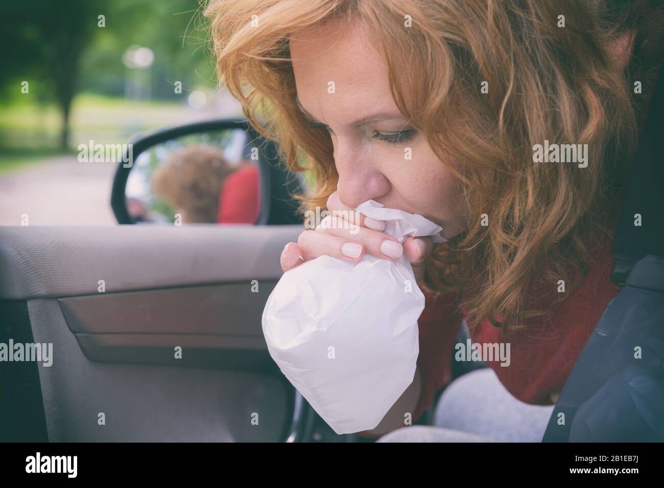 Woman suffering from motion sickness in a car and holding sick bag