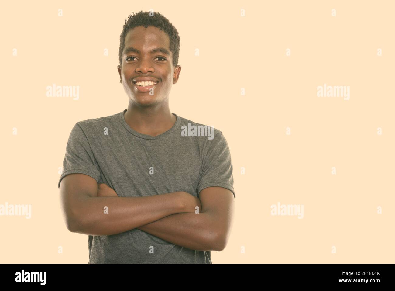 Studio shot of young happy black African teenage boy smiling with arms ...