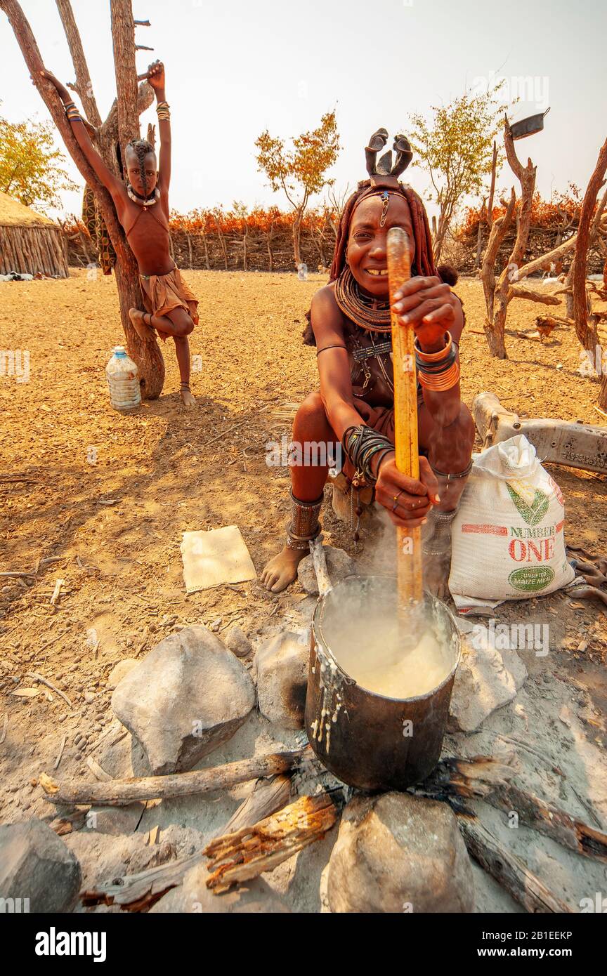 Himba woman cooking their staples food made with corn meal at his village near Epupa Falls, Namibia Stock Photo