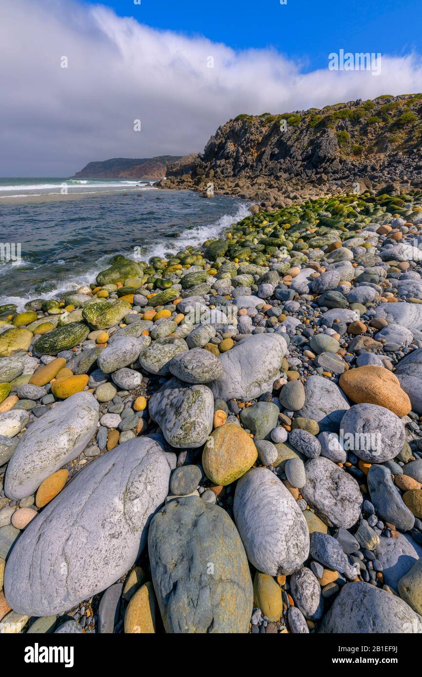 Coastal fog and pebbles, Praia do Abano, Portugal. Mists forming daily on the still cold sea in May, Cape Roca Region, Portugal Stock Photo
