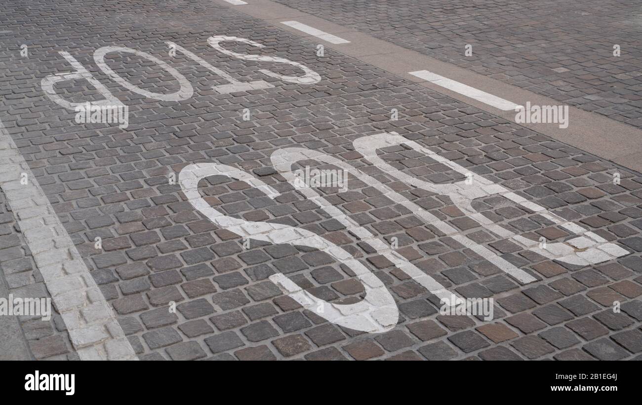 Bus stop sign painted in white color on the tiles on the road. Stock Photo