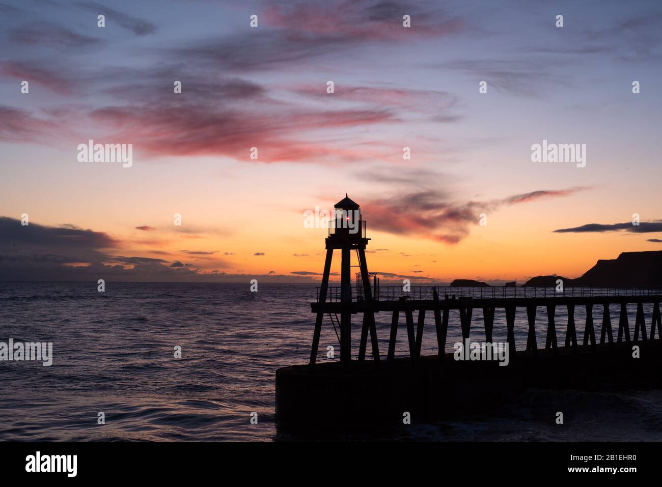 A view of the sunrise over the East Pier at Whitby, North Yorkshire. Stock Photo