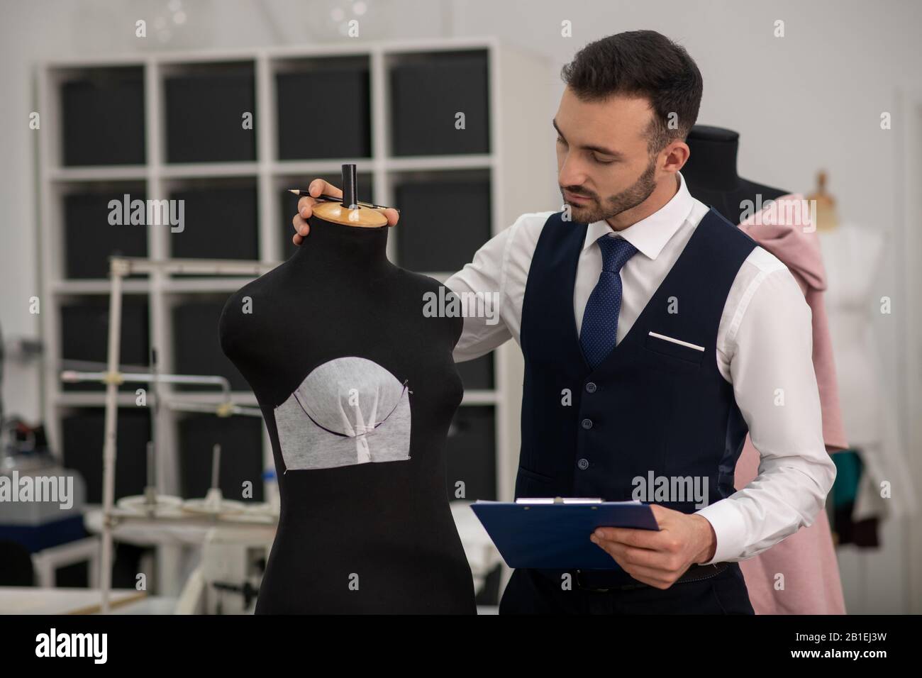 Male tailor touching dummy, creating new model Stock Photo