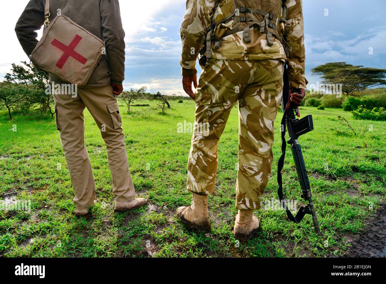 Armed rangers walking in a conservancy near the park, Masai Mara national park, Kenya. Stock Photo