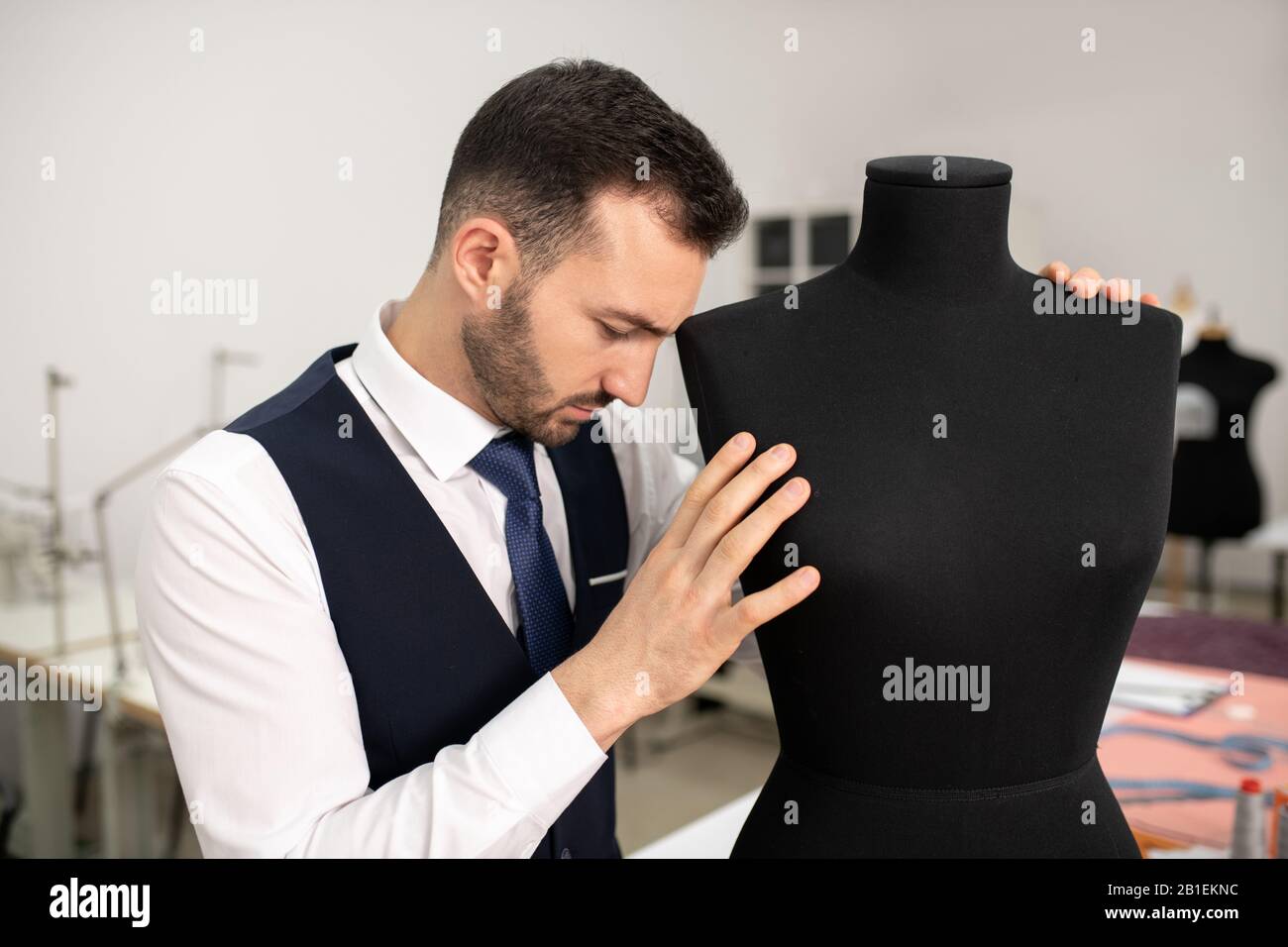 Male fashion designer bending head down on dummy Stock Photo