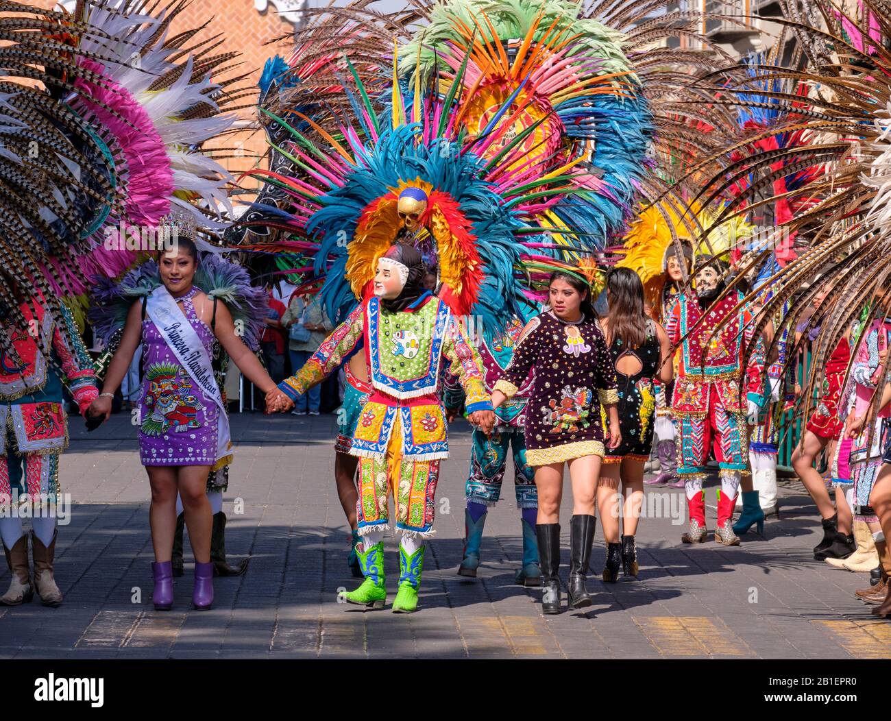 Line up of Dancers wearing Mask with faces and feathers, part of a