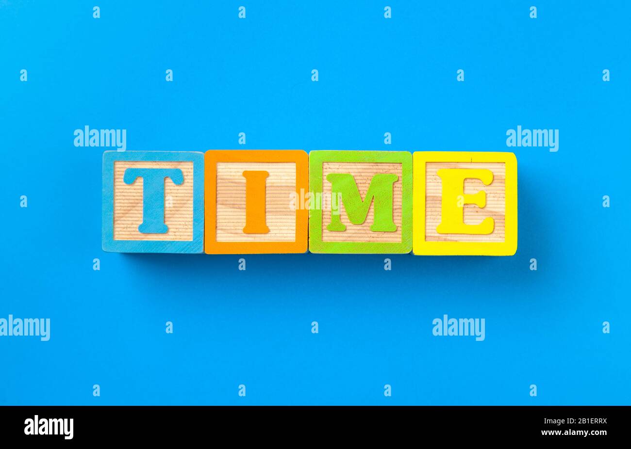Time. Wooden colorful alphabet blocks on blue background, flat lay, top ...