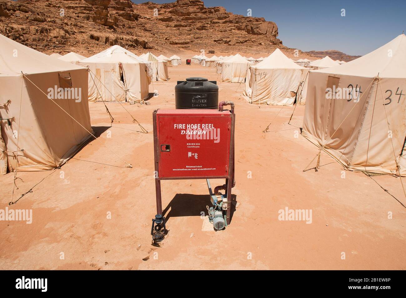 Wadi Rum, Jordan - April 28, 2009: A red fire hose reel locker and water tank attached stands between rows of tents at the Jabal Rum camp in Wadi Rum Stock Photo